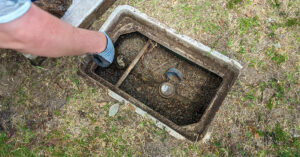 Water service line hole with person arm pointing