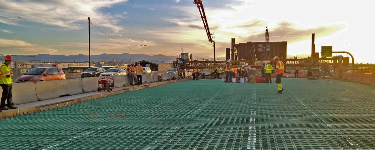 workers and equipment on bridge at sunset