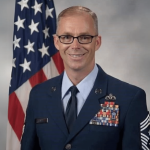 Photo of Kleinfelder Senior Project Controls Manager and Veteran Timothy Bayes in uniform with American flag in background