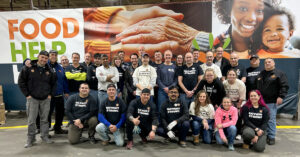 Volunteer group poses in front of food bank banner