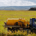 Stock photo of truck distributing sewage sludge into farm field