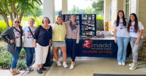 Group poses with Mothers Against Drunk Driving table at golf event