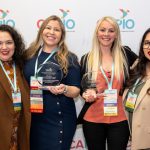 CAPIO25 four attendees at conference holding award in front of logo background