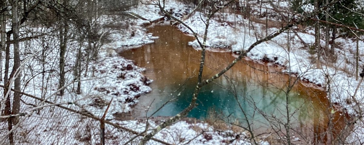 Hawk Run mine discharge in pool of water surrounded by snow and trees