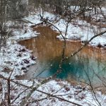 Hawk Run mine discharge in pool of water surrounded by snow and trees