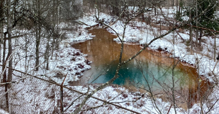 Hawk Run mine discharge in pool of water surrounded by snow and trees