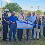 Group stands at Keach Family Library rain garden ribbon cutting