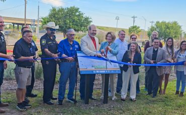 Group stands at Keach Family Library rain garden ribbon cutting