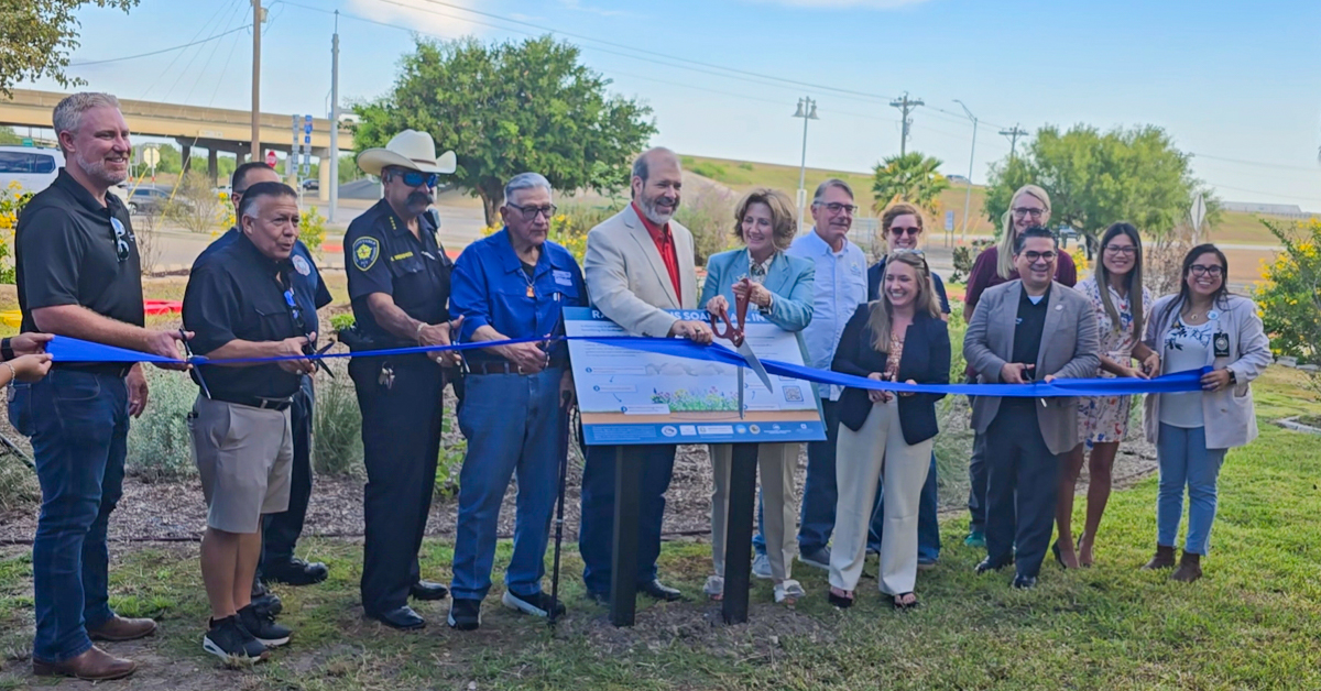 Group stands at Keach Family Library rain garden ribbon cutting