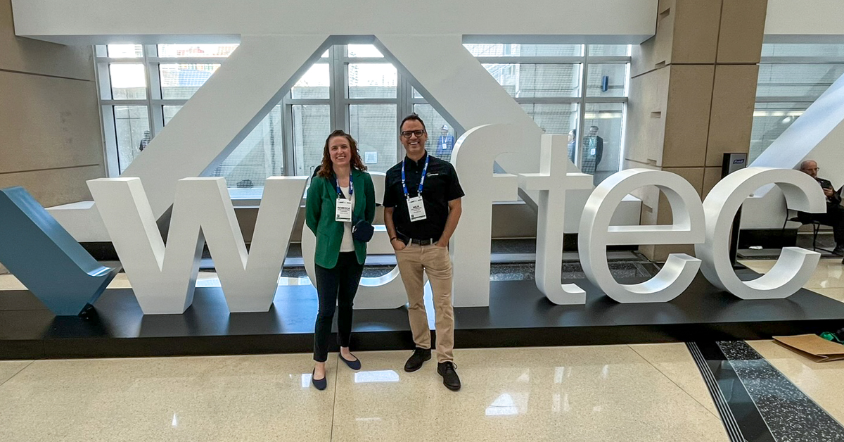 Two people stand with WEFTEC conference sign