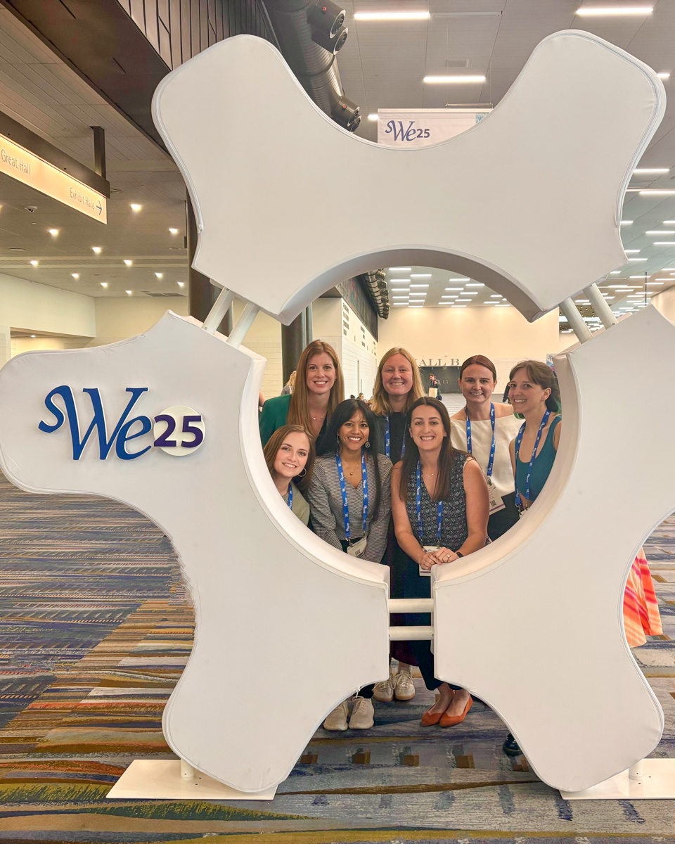 Group poses with event sign at SWE WE25 event