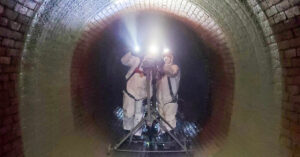 Two people in safety gear spraying tunnel