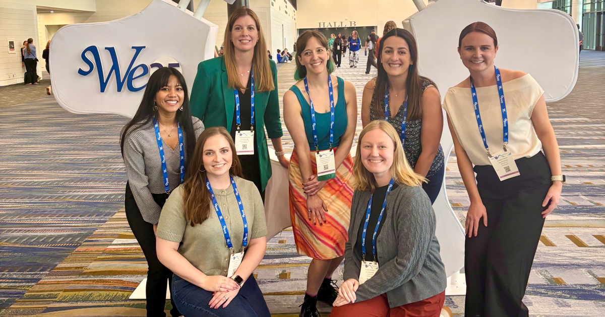 Group poses with event sign at SWE WE25 event
