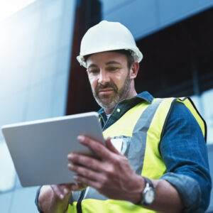 Tablet, engineer and man with helmet on construction site for development or building in city on project. Male person, tech and architecture as manager for progress in industrial, design and safety.