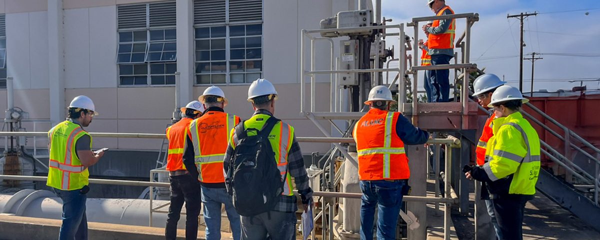 San Diego Pump Station 1 group in safety gear standing in front of small white building