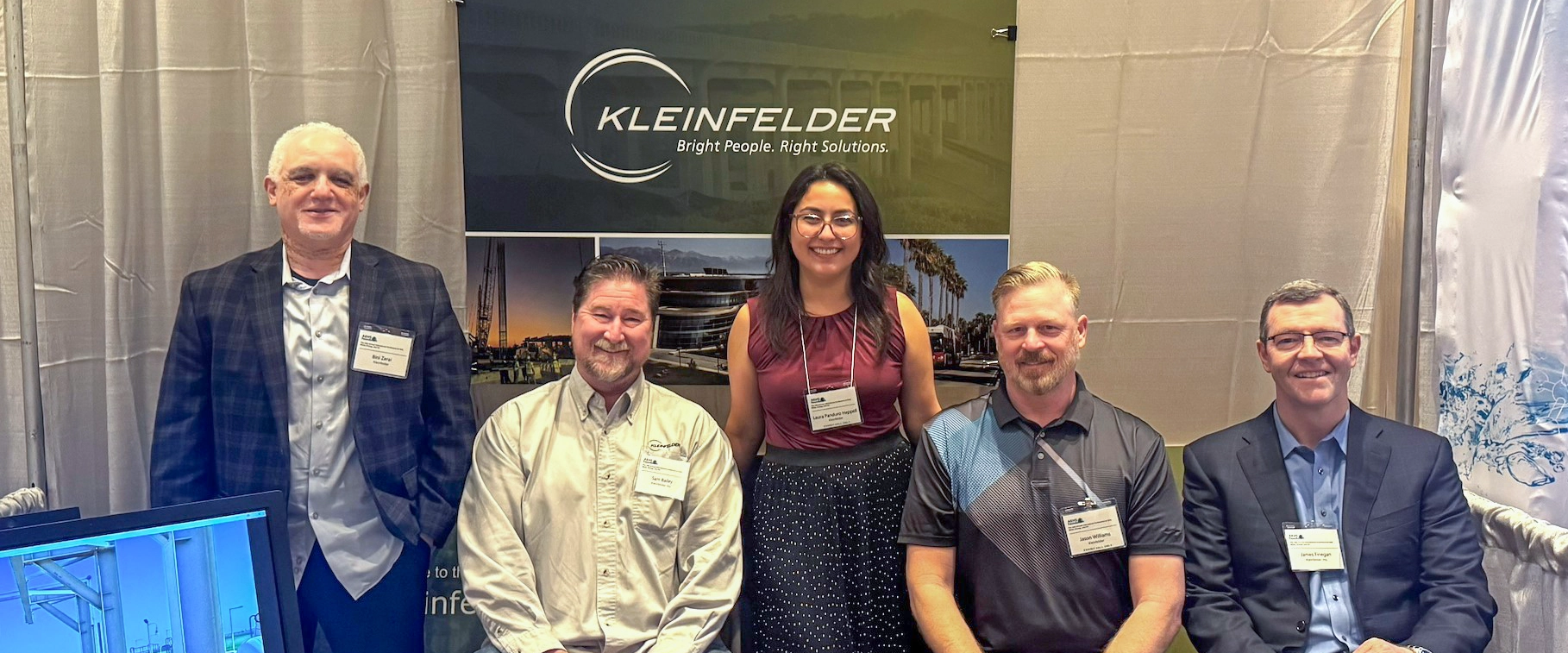 Five individuals pose in front of Kleinfelder sign at AEHS 2025 conference