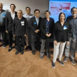 Group standing in front of screen posing for photo