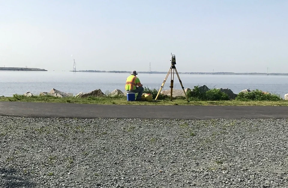 Kleinfelder surveyor sits next to surveying equipment and looks at water
